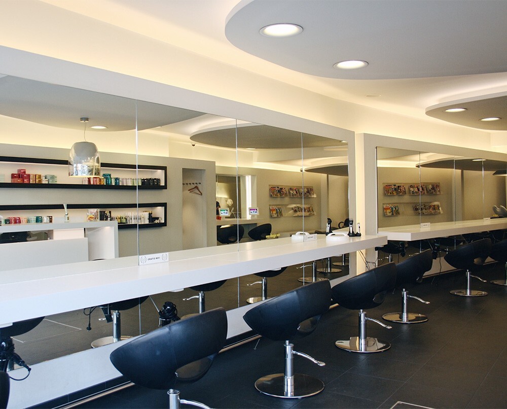 Interieur van een moderne kapsalon met witte spiegels, zwarte kappersstoelen en een gestileerde inrichting.